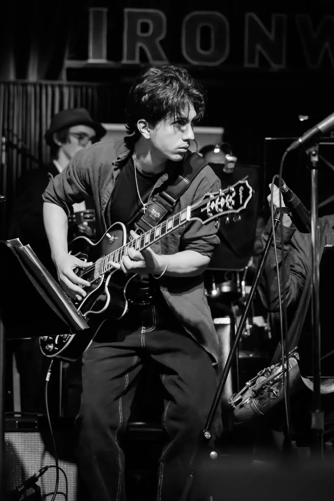Simon Maxam playing electric guitar on stage, black and white